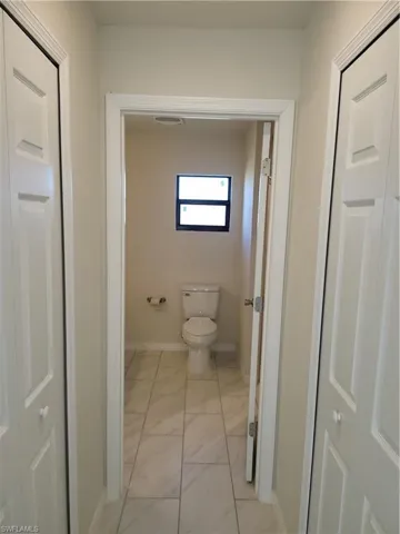 Bathroom featuring toilet and light marble finish floors