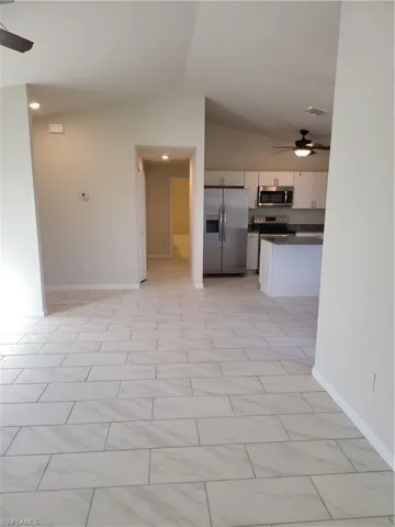 Kitchen with ceiling fan, fridge, white cabinets, lofted ceiling, and open floor plan