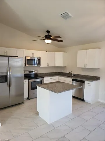 Kitchen with fridge, stainless steel stove, white cabinetry, and dishwasher
