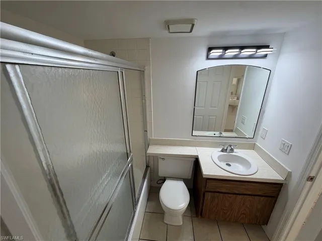 Bathroom with vanity, light tile patterned floors, and combined bath / shower with glass door