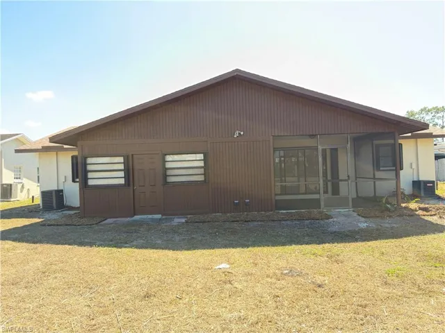 Rear view of house with a lawn and a sunroom
