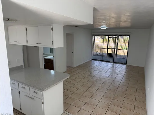 Kitchen with white cabinets, light stone countertops, and light tile patterned flooring
