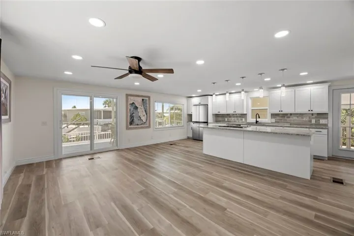 Kitchen featuring open floor plan, hanging light fixtures, white cabinetry, tasteful backsplash, and a center island