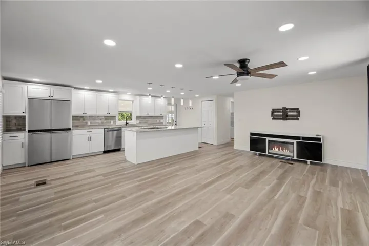 Kitchen with open floor plan, white cabinetry, recessed lighting, a kitchen island, and appliances with stainless steel finishes