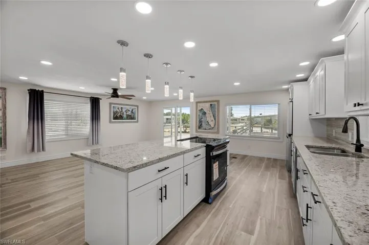 Kitchen featuring white cabinetry, light stone countertops, decorative light fixtures, black electric range, and recessed lighting