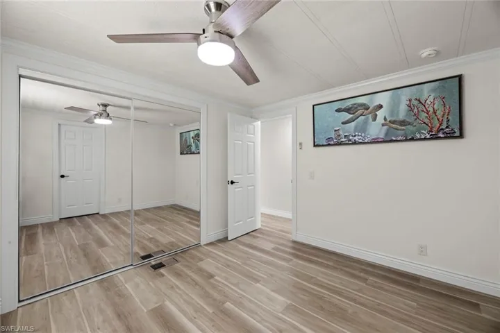 Unfurnished bedroom with a closet, light wood finished floors, crown molding, and ceiling fan