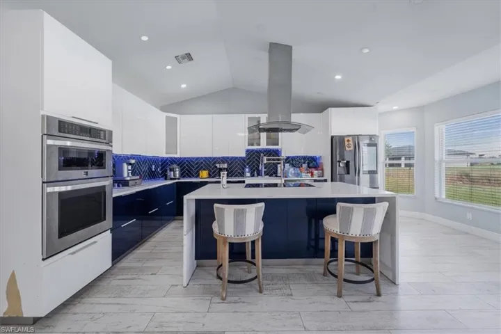 Kitchen featuring appliances with stainless steel finishes, a kitchen island, light hardwood / wood-style floors, white cabinets, and a breakfast bar