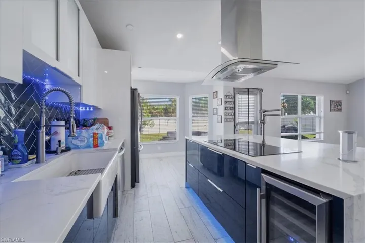 Kitchen featuring light hardwood / wood-style floors, stainless steel appliances, decorative backsplash, and white cabinets