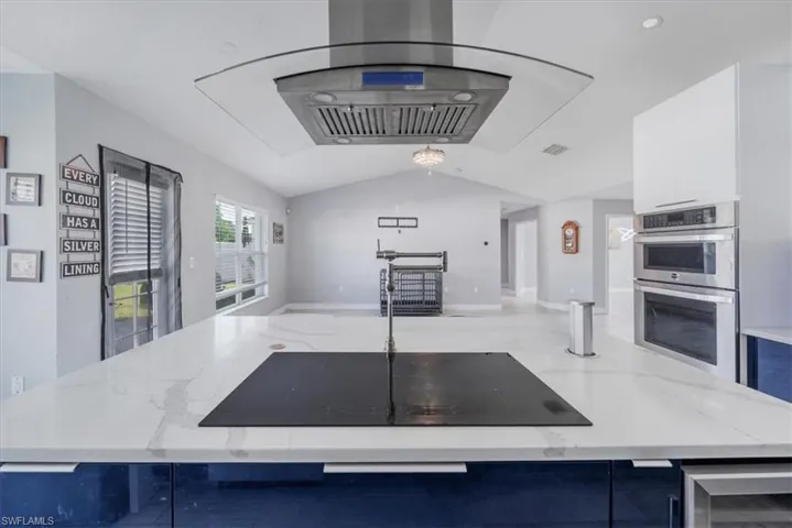 Kitchen with white cabinetry, light stone counters, sink, and backsplash