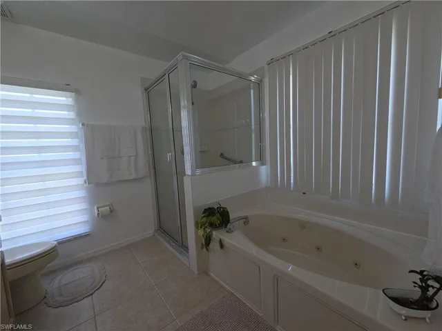 Bathroom featuring a tub with jets, a shower stall, and tile patterned floors