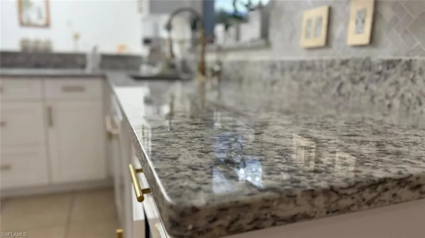 Kitchen view of light stone counters and white cabinets