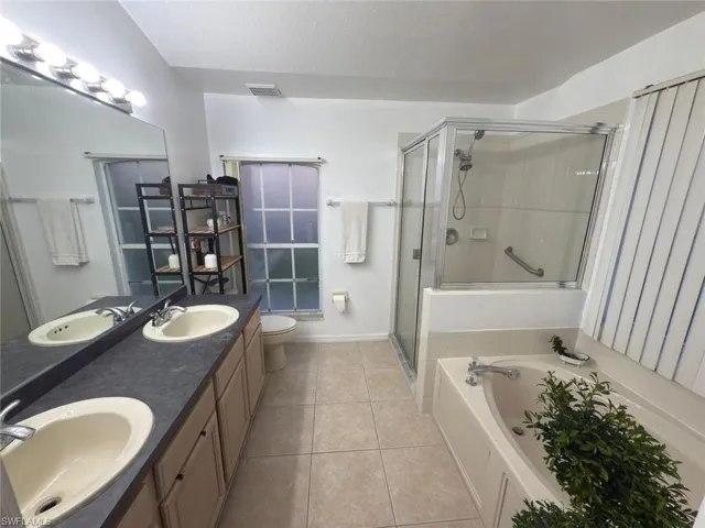 Full bathroom with double vanity, a bath, a stall shower, and tile patterned floors