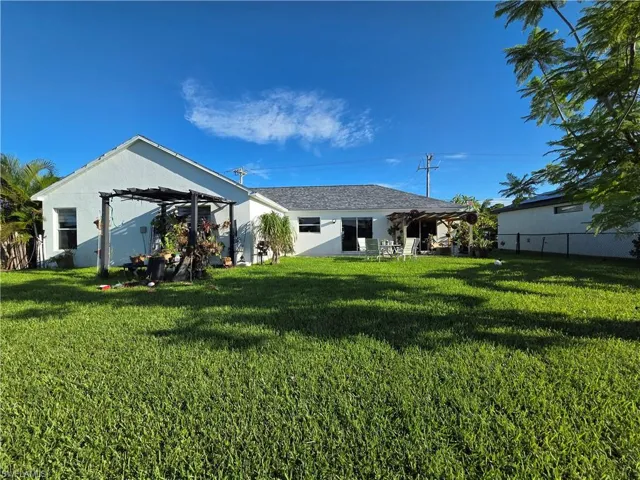 Rear view of property featuring stucco siding and a pergola