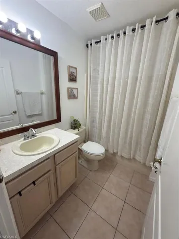 Bathroom with vanity, tile patterned floors, shower / bath combo, and a textured ceiling