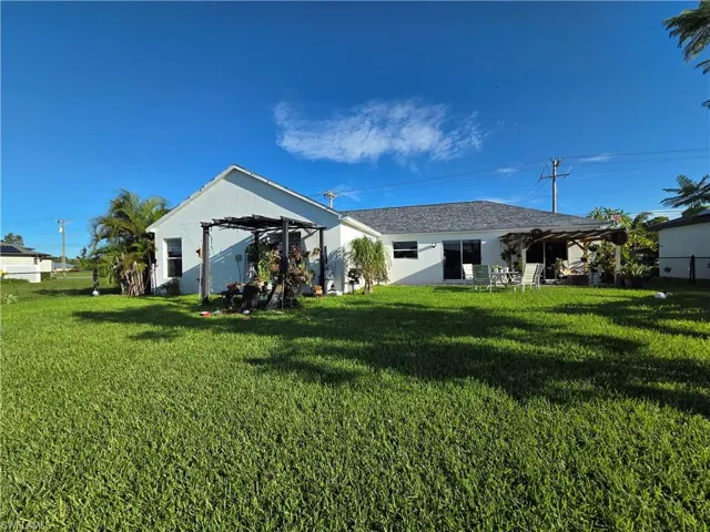Rear view of house with a pergola, a lawn, and stucco siding