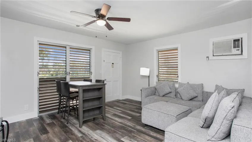 Living area featuring a ceiling fan, wood-style floors, baseboards, and a wealth of natural light
