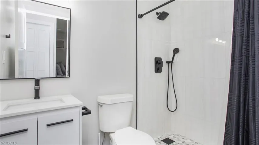 Full completely renovated bathroom with vanity, toilet, and a walk in tile shower