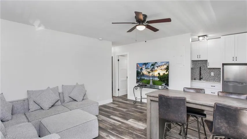 Living room featuring 5" baseboards, wood-style flooring, and a ceiling fan