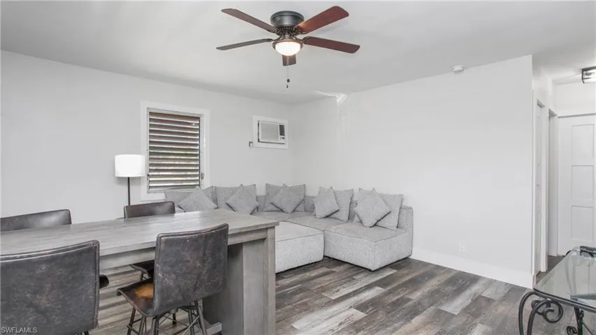 Living room featuring wood style floors, a wall mounted air conditioner, and ceiling fan