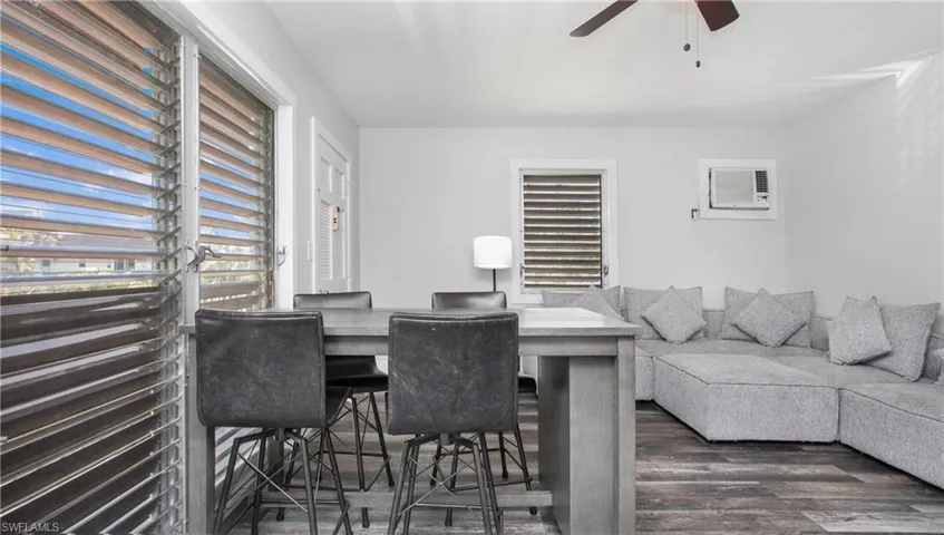 Living room featuring an AC wall unit, wood style floors, and a ceiling fan