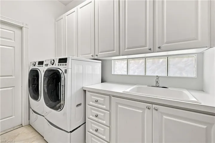 White shaker-style cabinetry, recessed lighting, drop-in utility sink, glass block window, and wood-finish flooring