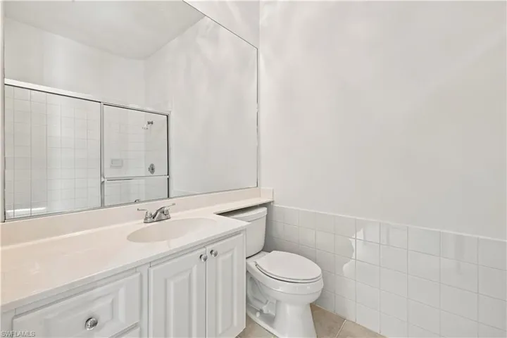 White vanity with recessed paneling and chrome hardware, a white undermount sink, and a light-colored countertop