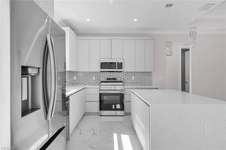 Kitchen with appliances with stainless steel finishes, light countertops, marble finish floor, ornamental molding, and backsplash