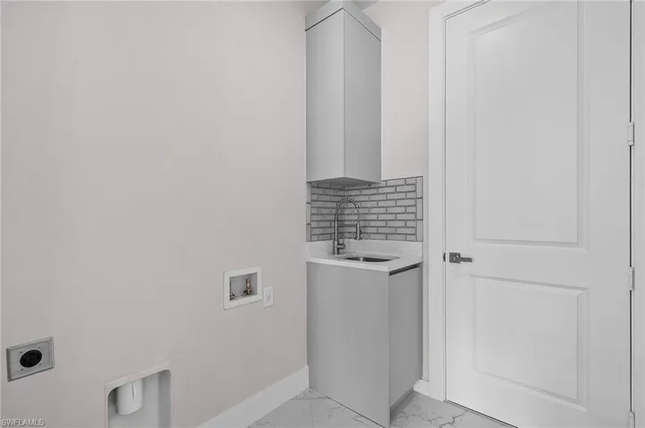 Laundry room with a sink, cabinet space, marble finish floor, hookup for a washing machine, and baseboards