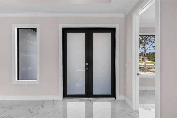 Entrance foyer with baseboards, crown molding, and marble finish floor