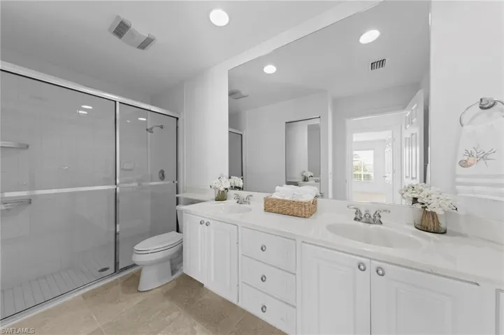 Full bathroom featuring double vanity, a shower stall, and recessed lighting