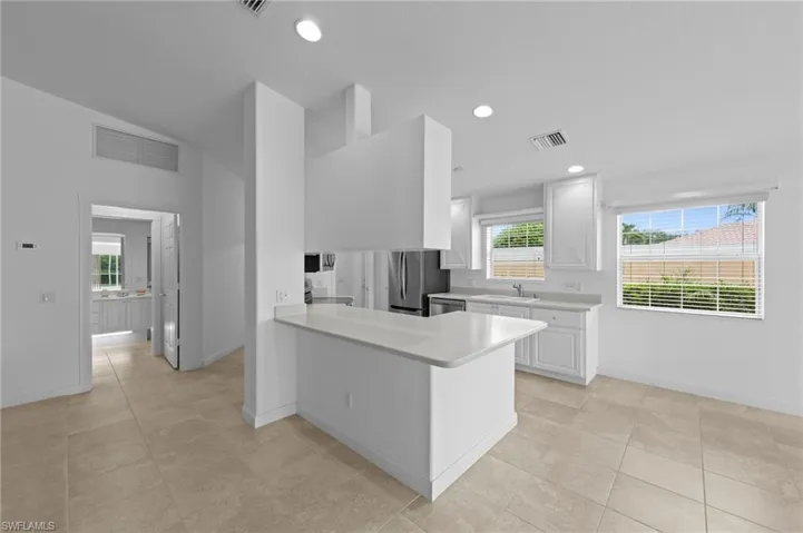 Kitchen featuring stainless steel appliances, light countertops, white cabinets, a peninsula, and recessed lighting