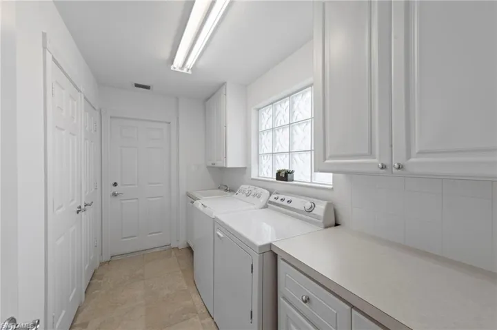 Laundry area featuring cabinet space, separate washer and dryer, and light stone finish floors