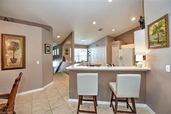 Kitchen featuring visible vents, white fridge with ice dispenser, a breakfast bar, a peninsula, and white cabinetry