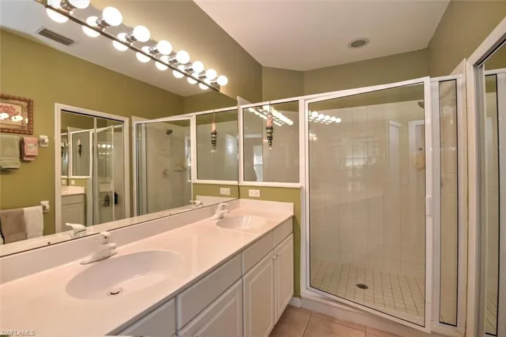 Full bath with a shower stall, tile patterned floors, visible vents, and a sink