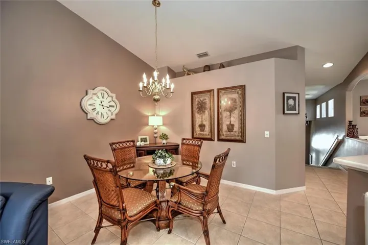 Dining area featuring arched walkways, a notable chandelier, visible vents, and light tile patterned flooring