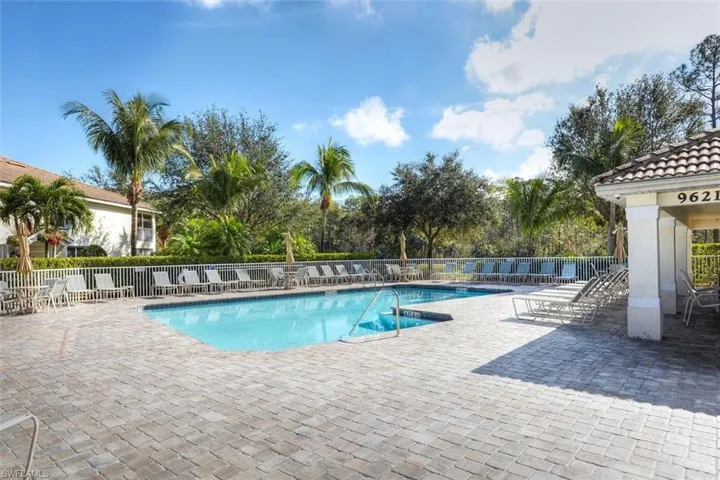 Community pool with a patio area and fence