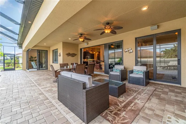 View of patio with glass enclosure, ceiling fan, and outdoor lounge area