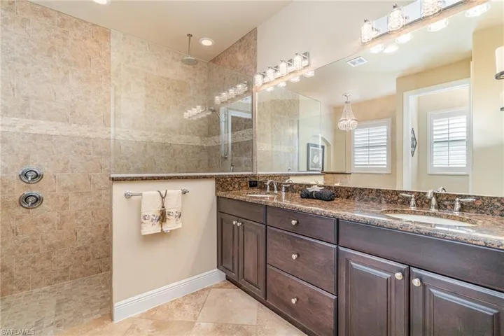 Bathroom featuring tile patterned flooring, vanity, and a tile shower