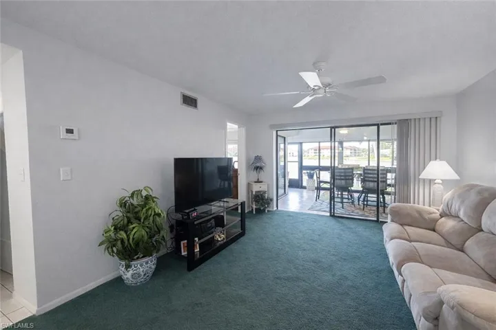 Carpeted living area featuring a ceiling fan and baseboards