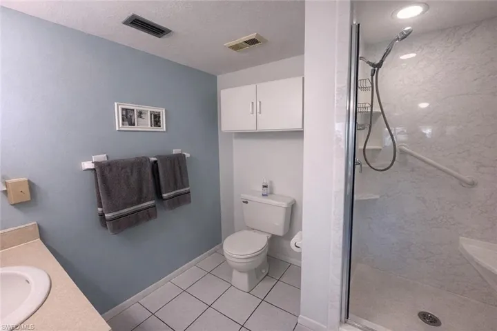 Bathroom with vanity, a shower stall, light tile patterned floors, and a textured ceiling