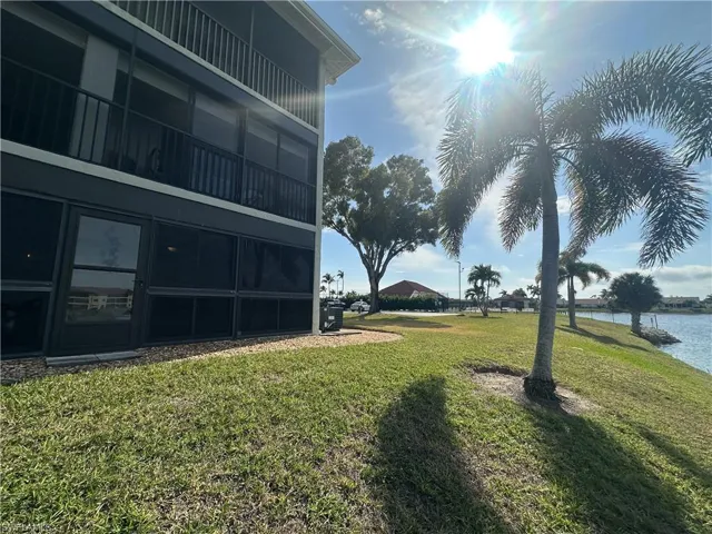 View of grassy yard with a balcony, a sunroom, and a water view