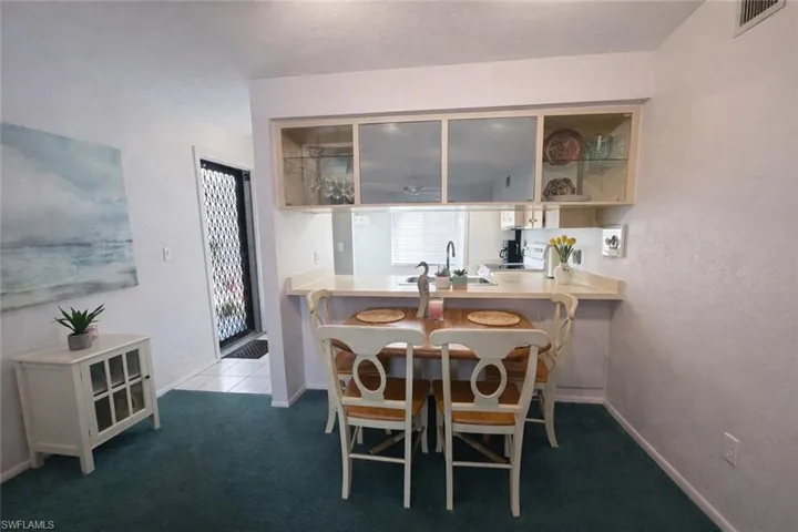 Kitchen featuring light countertops, a kitchen bar, glass insert cabinets, white electric range, and a peninsula