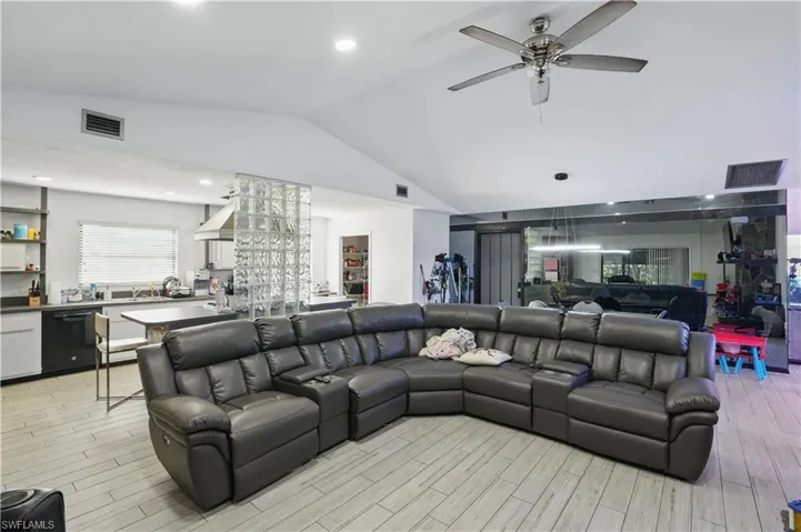 Living room with vaulted ceiling, light wood-type flooring, recessed lighting, and a ceiling fan