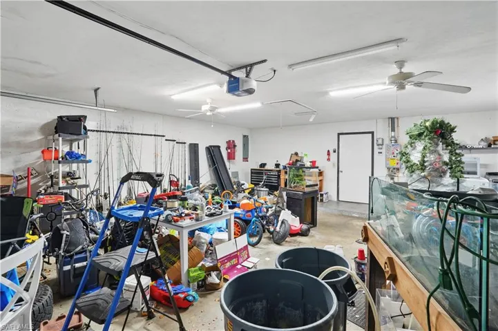 Garage featuring a ceiling fan, electric panel, a workshop area, and a garage door opener