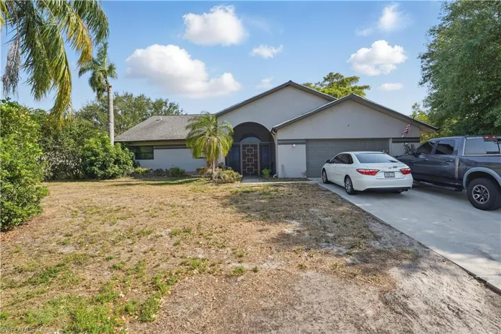 Single story home with driveway, a garage, stucco siding, and a front lawn