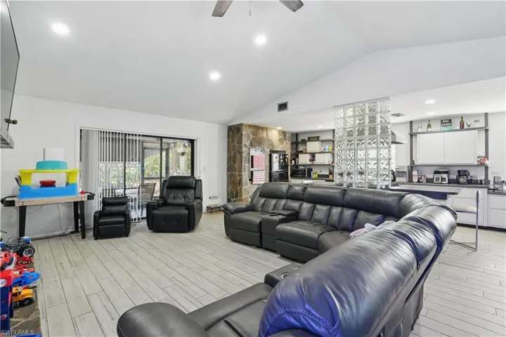 Living area featuring vaulted ceiling, light wood-type flooring, ceiling fan, and recessed lighting