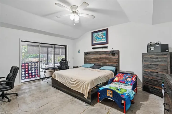 Bedroom featuring vaulted ceiling, concrete flooring, access to exterior, ceiling fan, and an office area