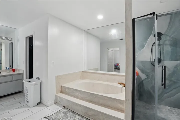 Full bathroom featuring a bath, vanity, a marble finish shower, tile patterned floors, and recessed lighting