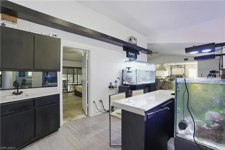 Kitchen featuring dark cabinetry, lofted ceiling, light wood-type flooring, and plenty of natural light