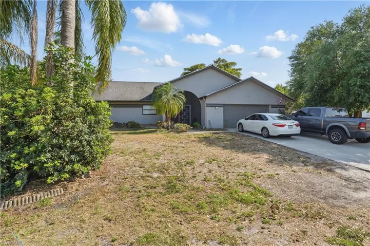Ranch-style home featuring concrete driveway, an attached garage, stucco siding, and a front lawn